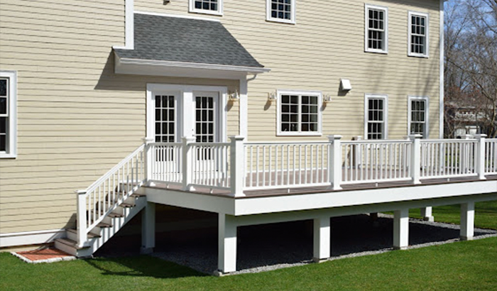 Front deck with railing and stairs leading to door, featuring siding repairs.